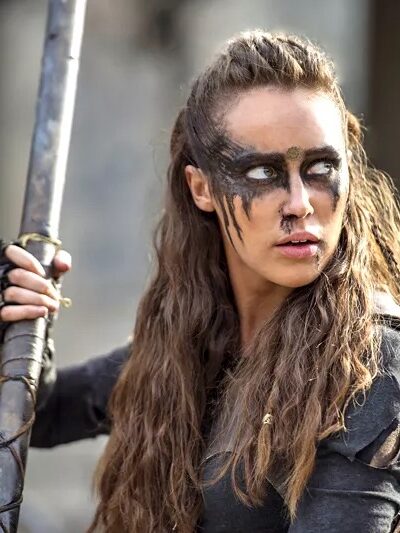 A lesbian superhero with long brown hair, face paint, dark outfit, holding a rod.