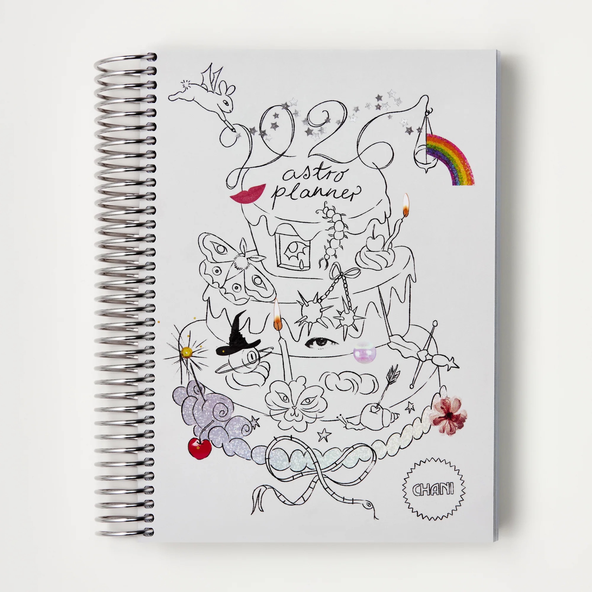 A planner with a white cover with illustrations and a spiral spine.