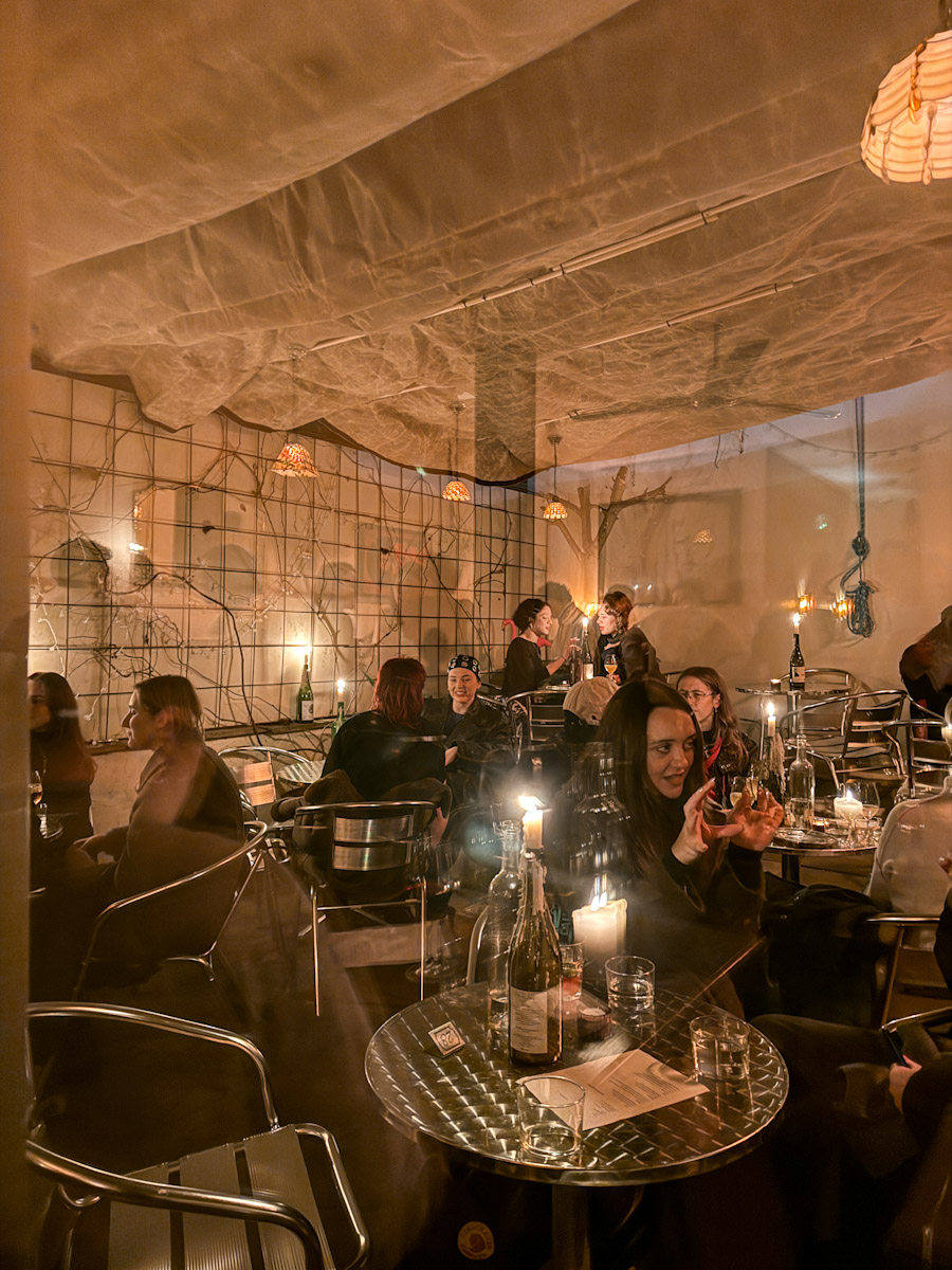 People sitting at tables socializing inside a lesbian space in London.