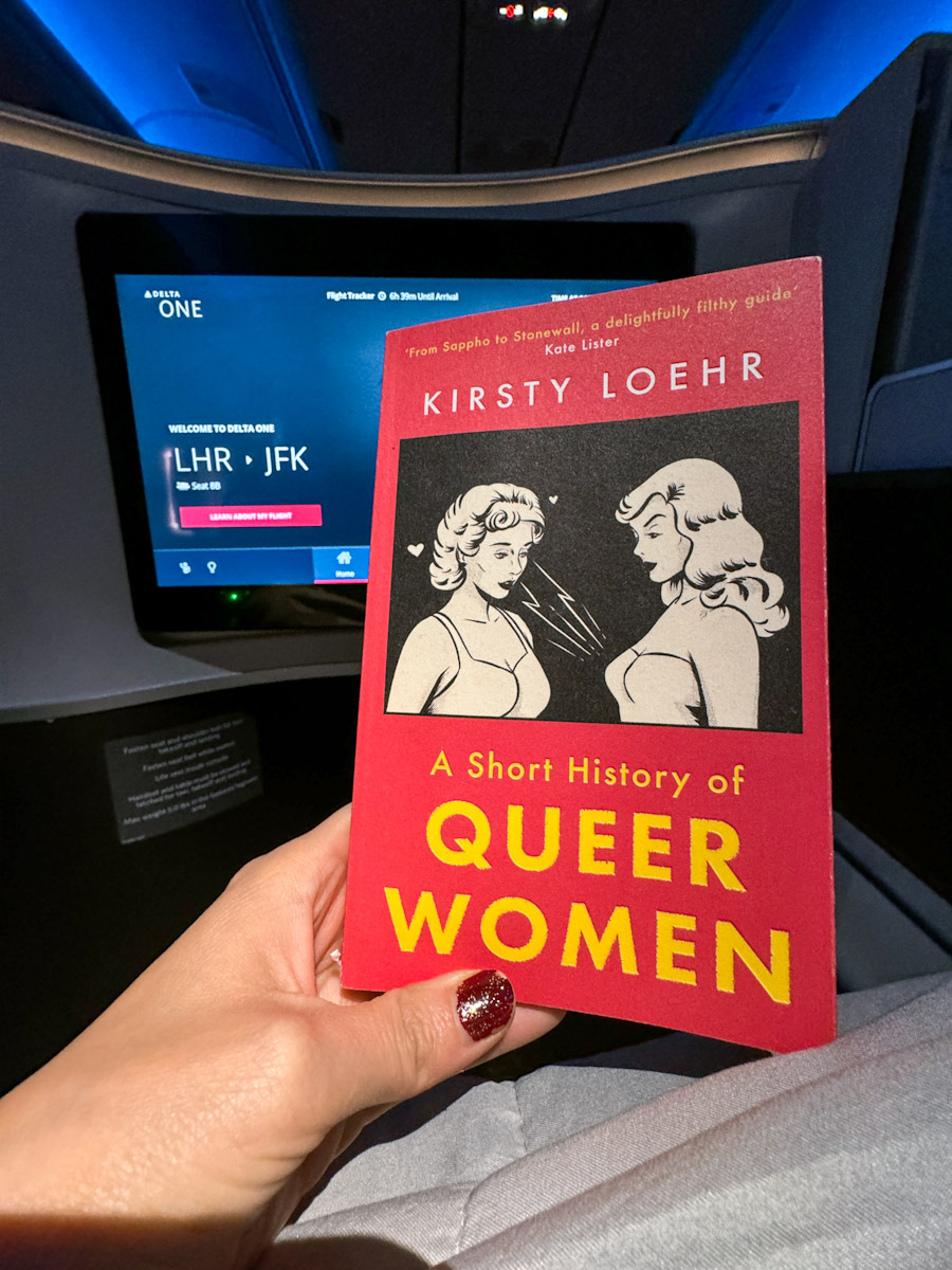 A queer book being held inside an airplane.
