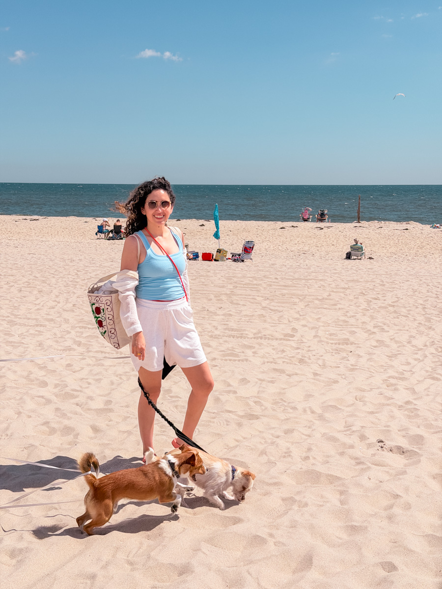 A woman with 2 dogs standing on the beach in Cherry Grove, Fire Island in New York.